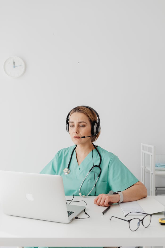 Female doctor using a laptop for online consultation in a medical office setting.