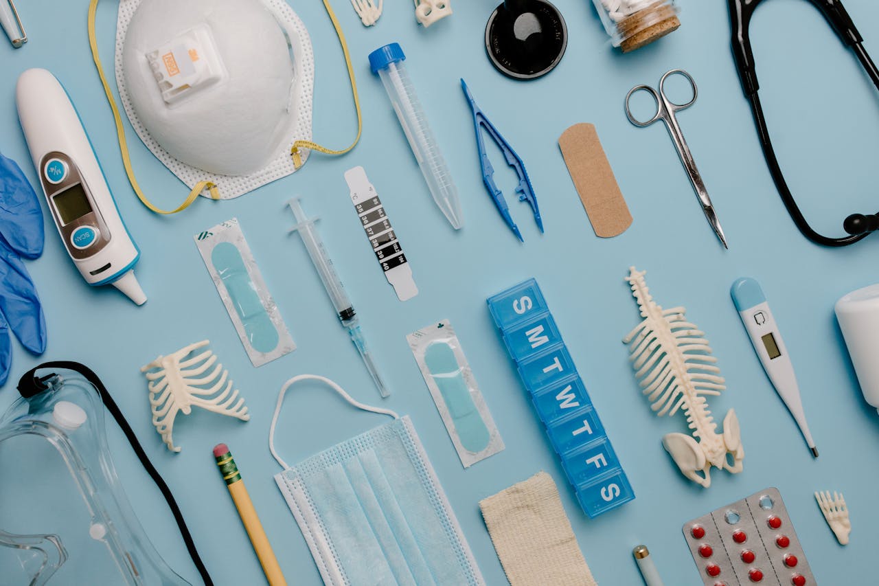 brand-01 A comprehensive flat lay of diverse medical supplies including PPE and diagnostic equipment on a blue surface.